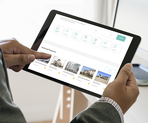 A person using a tablet to browse and book accommodations through an online platform with property listings displayed.