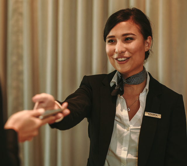 A person working at a hotel handing a room key to someone