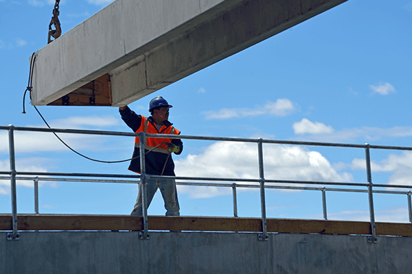 A person in a safety vest holding a metal beam A person in a safety vest holding a metal beam