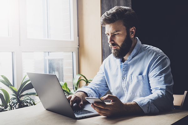 A person sitting at a desk with a computer and a phone
