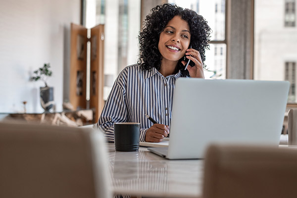 A person on the phone and looking at a computer