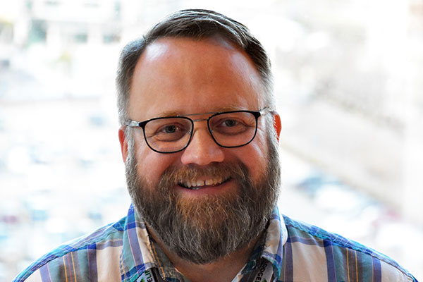 Professional headshot of LodgeLink team member in plaid shirt, smiling at the camera.