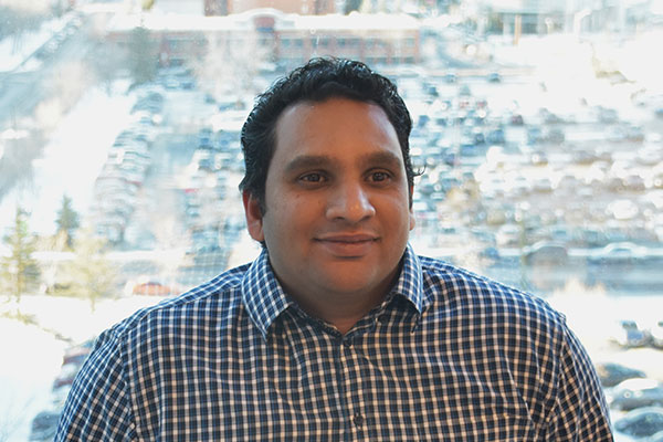 Professional headshot of LodgeLink team member in checkered shirt with office background.