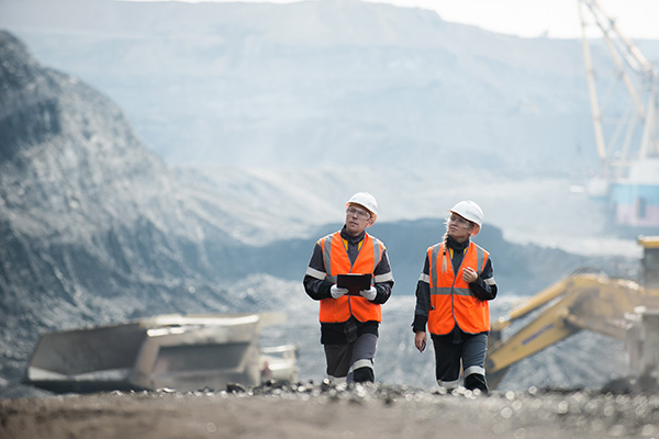 A couple of people wearing safety vests walking.