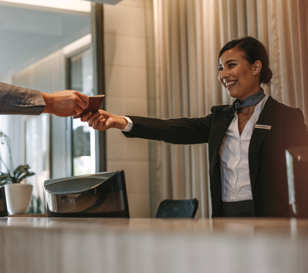 A hotel employee handing a hotel key to a guest.