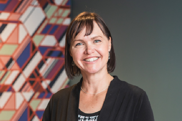 Professional headshot of LodgeLink team member with short dark hair, smiling against patterned wall.