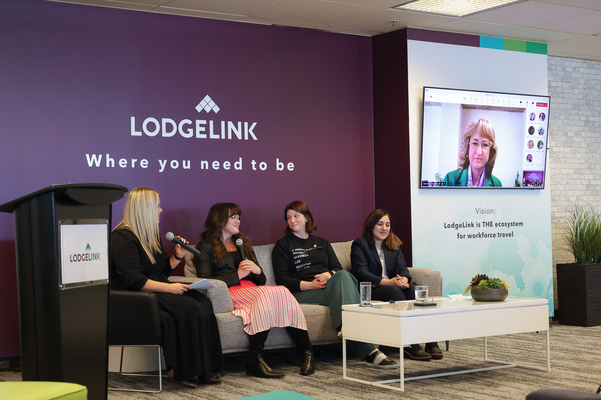 LodgeLink International Women’s Day event with panelist speaking and company branding on display.