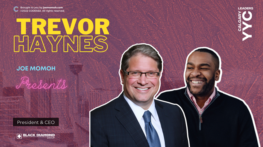 A professional image with two smiling men in business attire against a burgundy city backdrop.