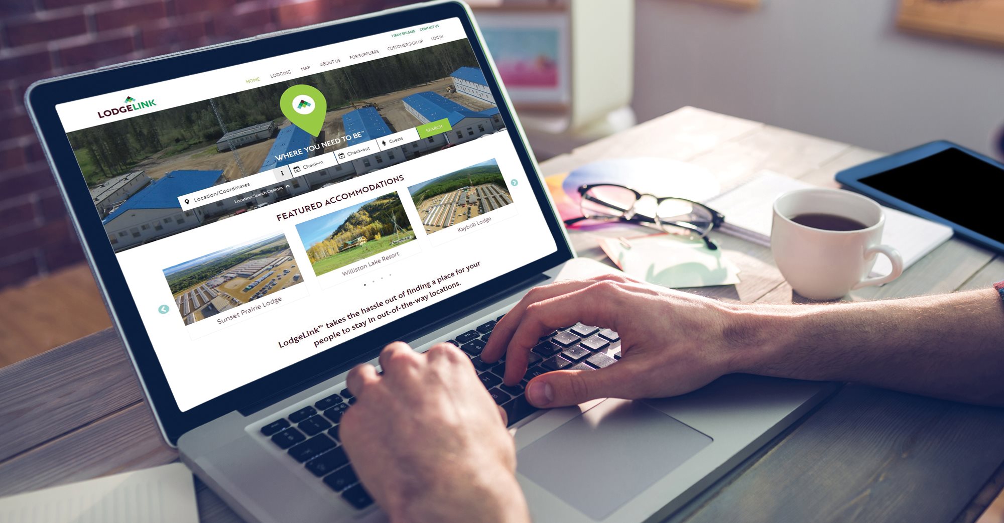 A person uses a laptop displaying a LodgeLink website with property listings
