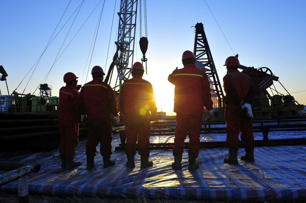 Construction crew on fracking site with sunset in the distance.