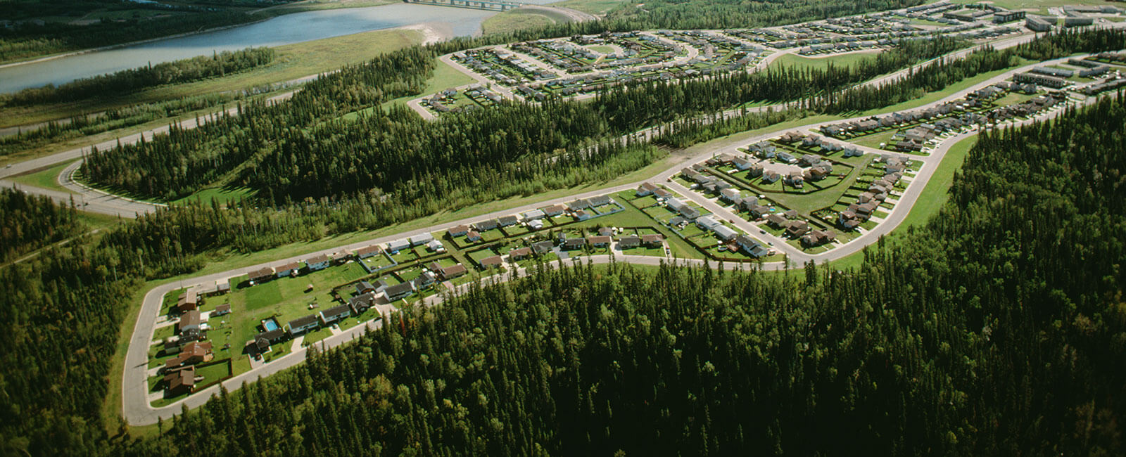 Aerial view of a serene forested landscape with winding roads connecting small residential areas.