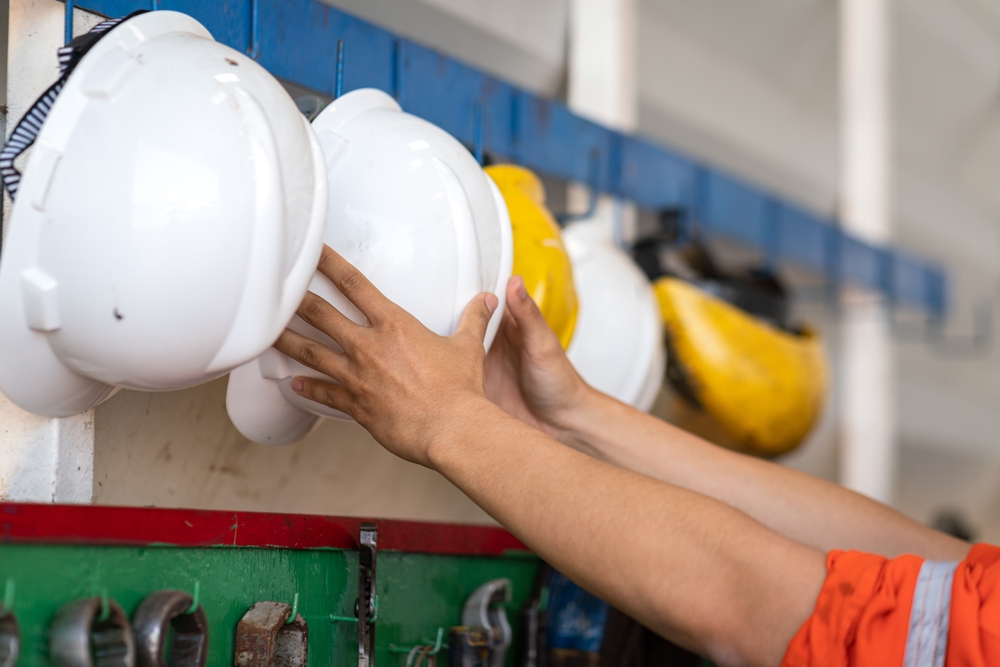 A person putting a hard hat on a hook