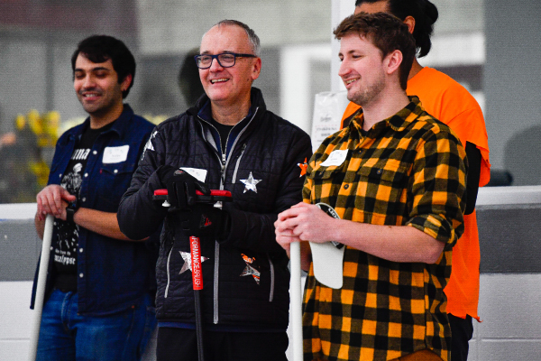 Colleagues standing together smiling at a curling event 