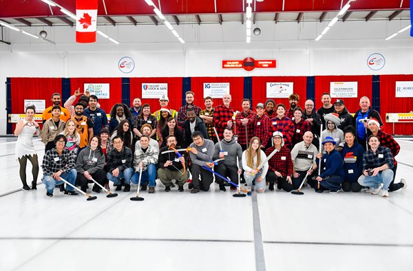 LodgeLink employees holding curling brooms at a company event 