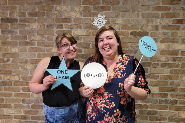 Two women holding signs posing for the camera at an event 