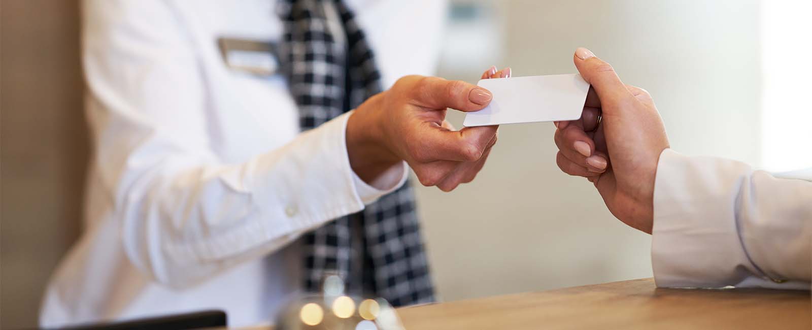 A close-up of a hotel employee handing a key card to a customer