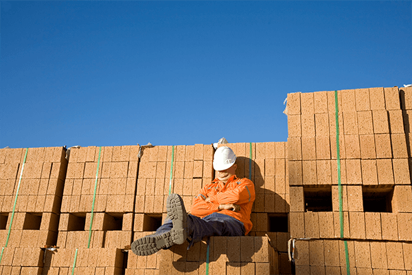 Construction worker sleeping on top of bricks