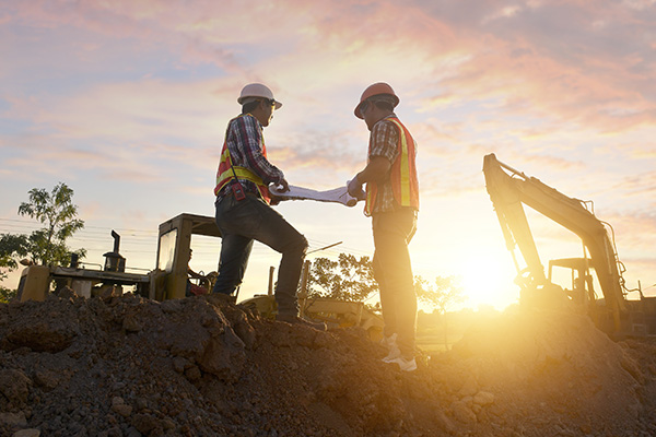 Construction workers on site with sunrise.