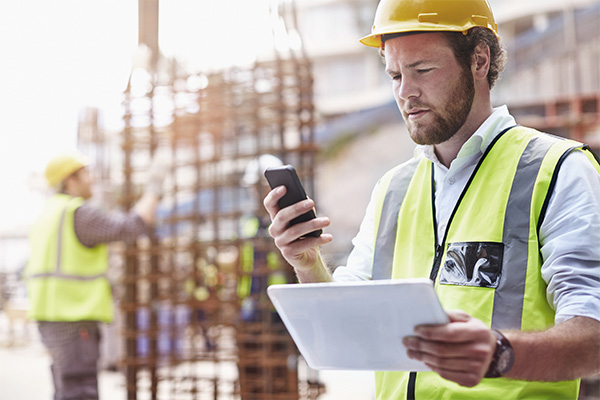 A man on his construction phone using travel management technology