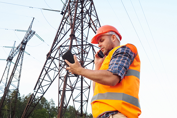 A construction worker on his phone while using a tablet showing travel management technology