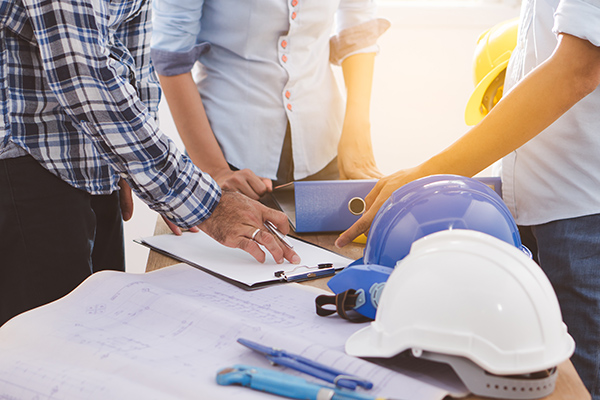 a group of construction workers with hard hats and blueprints.	