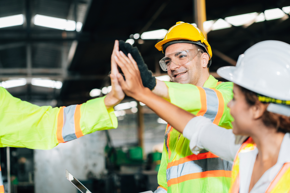 A group of workers with hard hats giving each other high fives